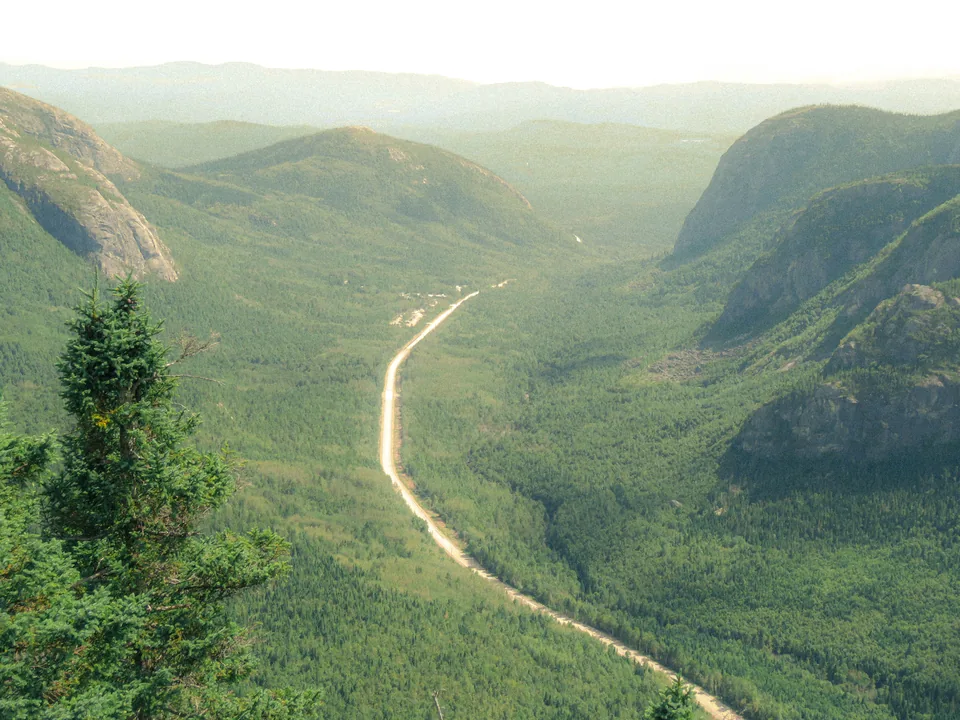 A long highway crossing a wide green mountain valley