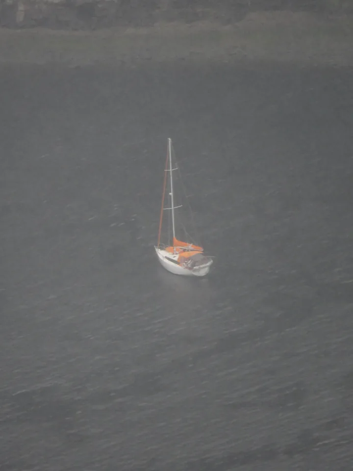 A small sailboat with an orange cover on dark water